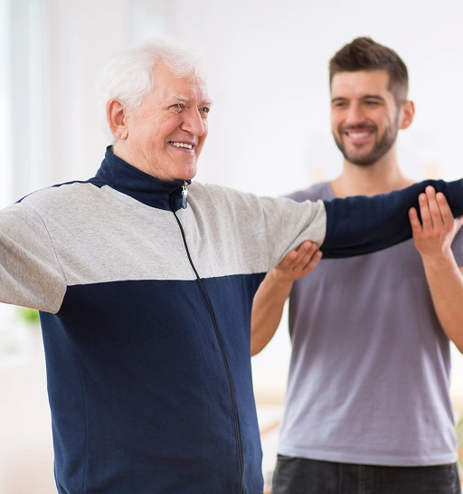 Older man smiling with arms outstretched, receiving support from a younger man in a casual setting, emphasizing compassionate care and connection in mental health treatment.