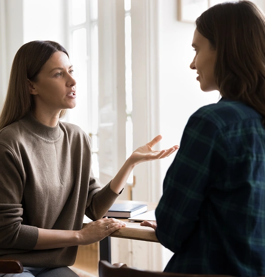 Two women engaged in a conversation during a family therapy session, discussing emotional support and communication strategies.