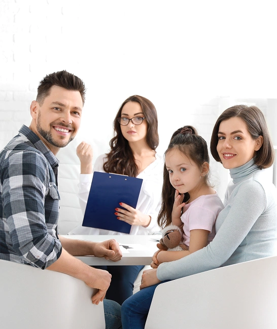 Family engaged in counseling session with therapist, discussing communication and relationship improvement, featuring a smiling couple and their child holding a toy.