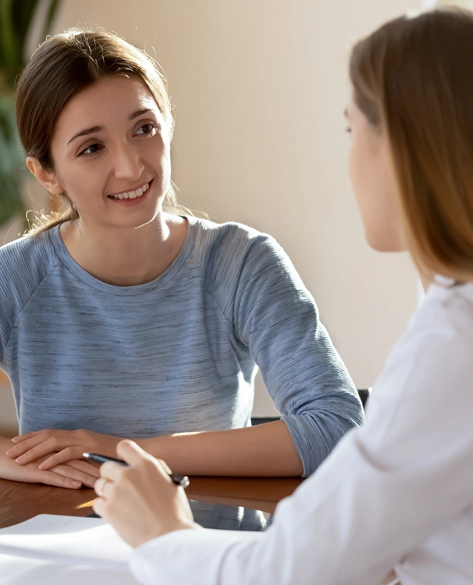 Woman engaged in a counseling session, smiling and listening attentively to a therapist, highlighting supportive family counseling services.